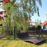 Garden with lounge chair and table, surrounded by trees and a fence.