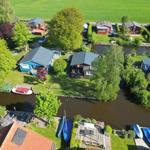 Aerial view of canal houses with boats and green lawns.