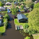 House by canal with boat and green surroundings