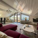 Living and dining area with red sofa, TV, and view of balcony.