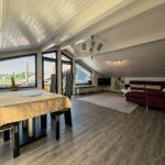 Living and dining area with red sofa, dining table, and large window view.