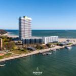 Hochhaus am Strand mit Hafen und Bootsanlegern. Blick auf das Meer und angrenzende Gebäude.