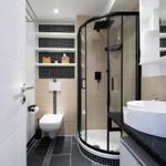Badezimmer mit Dusche, Waschbecken und Toilette. Schwarze und weiße Fliesen.
