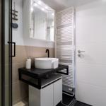 Badezimmer mit Waschbecken, Spiegel und Dusche