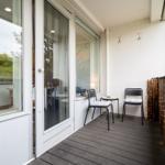 Terrasse mit zwei Stühlen und Tisch, Holzgeländer mit Lichterkette, Blick in Wohnraum.