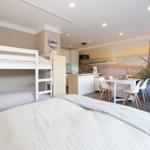 Zimmer mit Doppelbett, Etagenbett und Küchenbereich mit Kücheninsel.