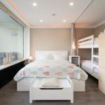 Schlafzimmer mit Doppelbett, Hochbett und großem Fenster zur Terrasse.