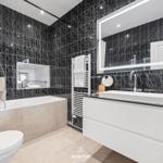 Badezimmer mit Dusche, Badewanne, Waschbecken und Spiegel