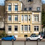Historisches Gebäude mit mehreren Stockwerken und Fenstern. Autos stehen vor dem Haus.