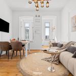 Wohn- und Essbereich mit Sofa, Esstisch und Wandbild mit Segelbooten.