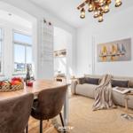 Essbereich mit Tisch und Stühlen, Wohnbereich mit Sofa und Wandbild.