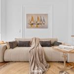 Ein Wohnzimmer mit Sofa, Kissen, Decke und Wandbild mit Segelbooten.