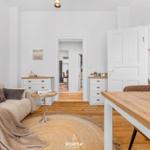 Wohn- und Essbereich mit Sofa, Holztisch und Schubladenkommoden.