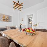 Essbereich mit Holztisch, Sitzgelegenheiten und Obstschale. Küche im Hintergrund.