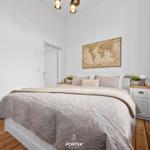 Schlafzimmer mit Bett, Nachttisch und Weltkarte an der Wand.