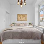 Schlafzimmer mit Bett, Wandkarte und Fenster. Holzfußboden und Deckenleuchte.