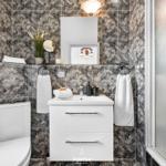 Badezimmer mit Marmorfliesen, Waschbecken, Toilette und Dusche