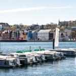 Hafen mit Bootsanlegern und Blick auf historische Gebäude im Hintergrund.