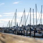 Hafen mit Segelyachten und Blick auf Stadt im Hintergrund.