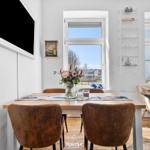 Esszimmer mit Holztisch, braunen Stühlen und Blick auf den Hafen.