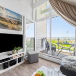 Living room with TV, balcony, and sea view.