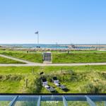 Two lounge chairs on green grass with view of harbor and sea.