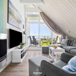 Living room with fireplace, TV, and balcony view of the sea.