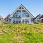 Modern vacation homes with large windows and terraces in a green setting.