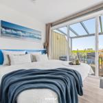 Bedroom with balcony and sea view. Bed with blanket, wall art, and nightstand.