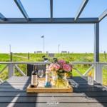 Terrace with table, chairs, and flowers. View of green grass and flag.