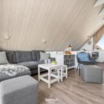 Living room with gray sofa, white tables, and wooden ceiling.