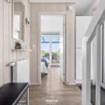 Hallway with wooden walls, mirror, and view into bedroom with terrace.