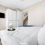 Bedroom with bed, wardrobe, and TV on wood wall