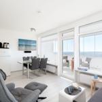 Living room with dining area, sea view, and modern furnishings.
