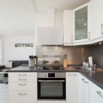 Kitchen with white cabinets, dark countertop, and view into living room with sofa.