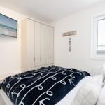 Bedroom with bed, wardrobe, and TV mounted on the wall.