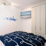 Bedroom with bed, wardrobe, and wall picture with light fixture.