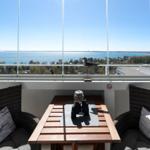 Balcony with table and two seating areas. View of lake and city.
