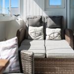 Terrace area with wicker sofa and anchor-patterned cushions.