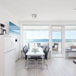Kitchen with dining table, TV, and sea view.
