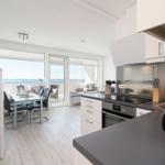 Kitchen with dining area and sea view through large windows.