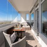 Terrasse mit Sitzgruppe und Tisch. Blick auf Landschaft. Glasgeländer und Holzboden.