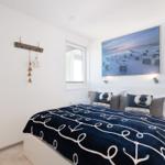 Schlafzimmer mit Bett, Wandbild und Fenster. Dekoration mit Strandmotiven.