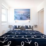 Schlafzimmer mit Bett, Wandbild und Fenster.