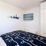 Schlafzimmer mit Bett, Kleiderschrank und Wandbild mit Leuchtturm.