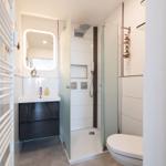Badezimmer mit Dusche, Waschbecken und Toilette.