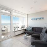 Wohnzimmer mit Blick auf den Ostsee, Sofa, Sessel und Balkon.