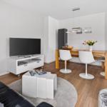 Living and dining area with TV, table and chairs on wooden floor.