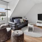 Living room with sofa, armchair, TV, and round rug.