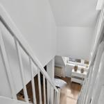 White staircase leading to living area with window and cabinet.